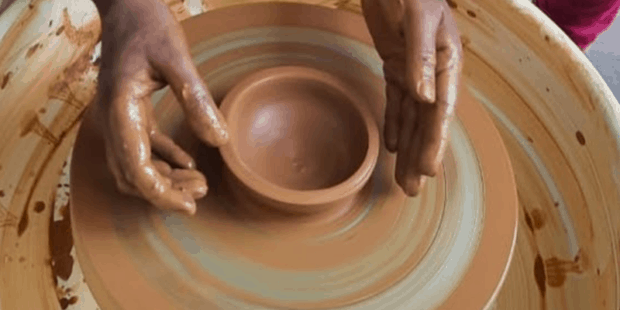 Close up shot of a hand preparing pot on clay pot making wheel.