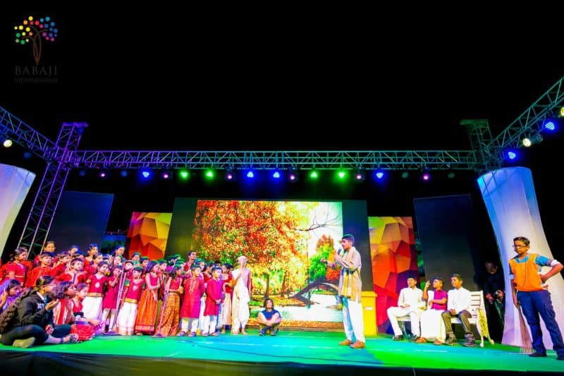 Group of School students on a stage with a boy holding a mic explaining about show.