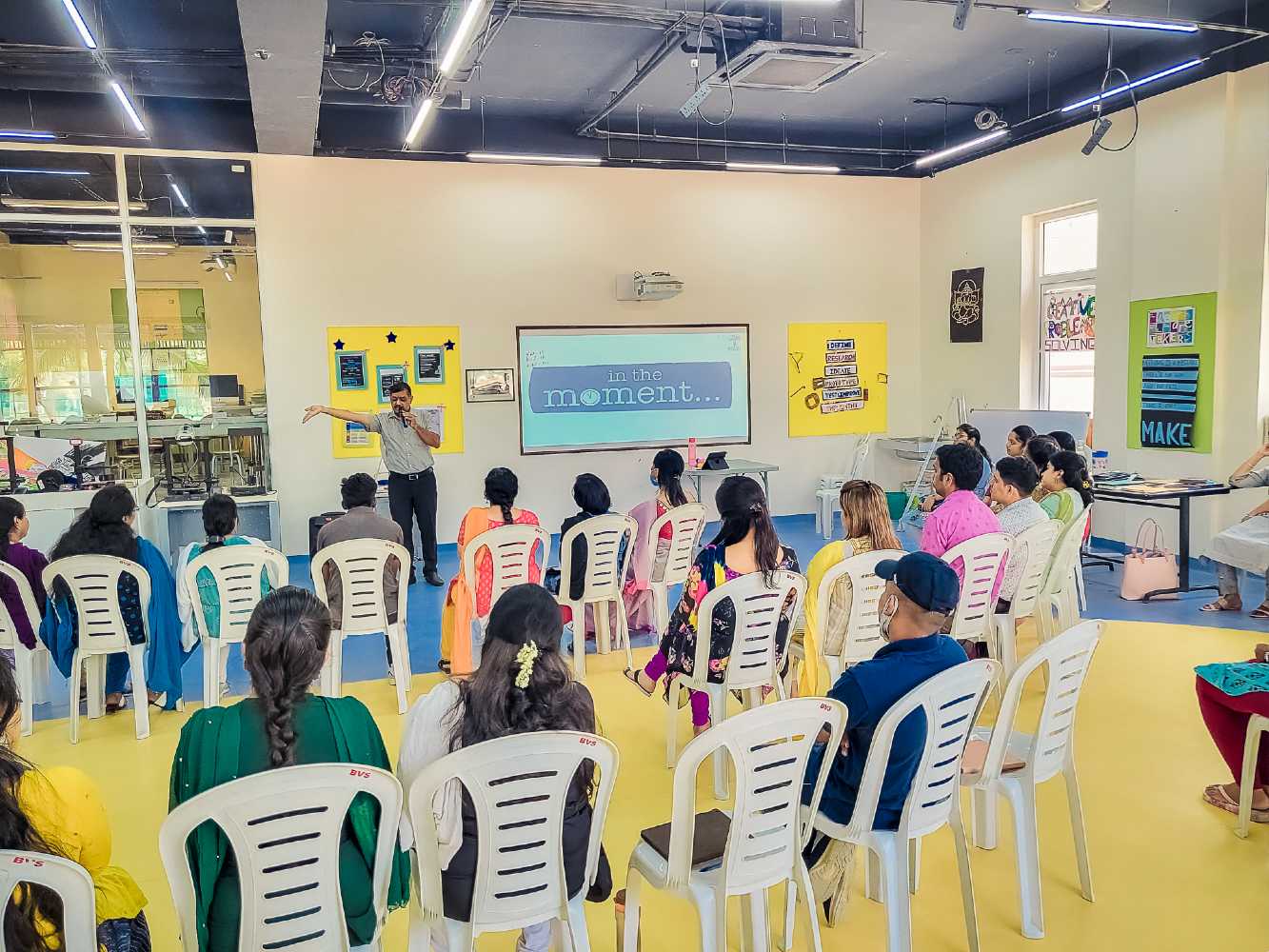 A motivational speaker is giving his speech to a group of teachers sitting on the chair in a cbse higher secondary school.