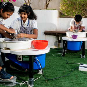 Two girl students and a boy is doing clay modelling.