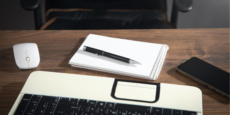 An image of a notepad and pen positioned in front of a laptop, ready for note-taking.