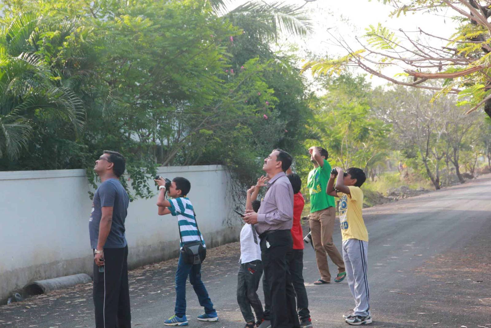 Three staff members and students are in the outdoor, viewing the top with binocular and camera.